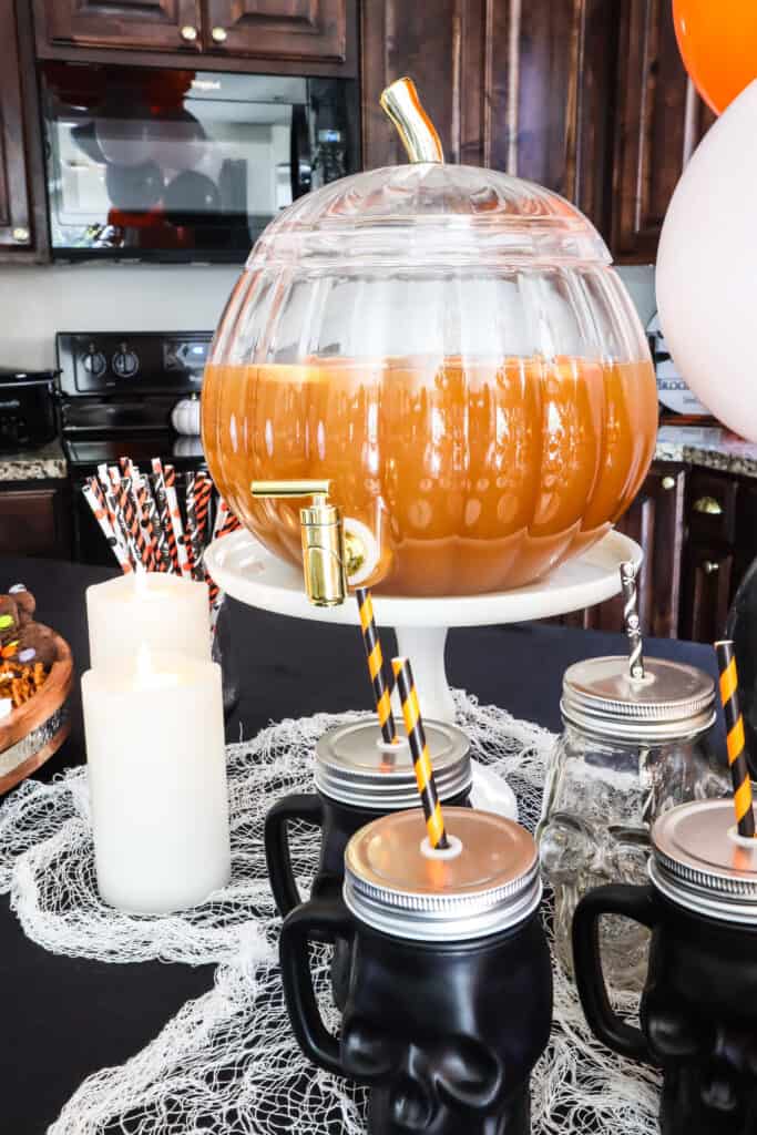 apple cider in a pumpkin drink dispenser for halloween movie party